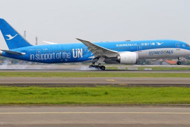 XiamenAir aircraft with UN support livery landing on runway, promoting sustainable goals.
